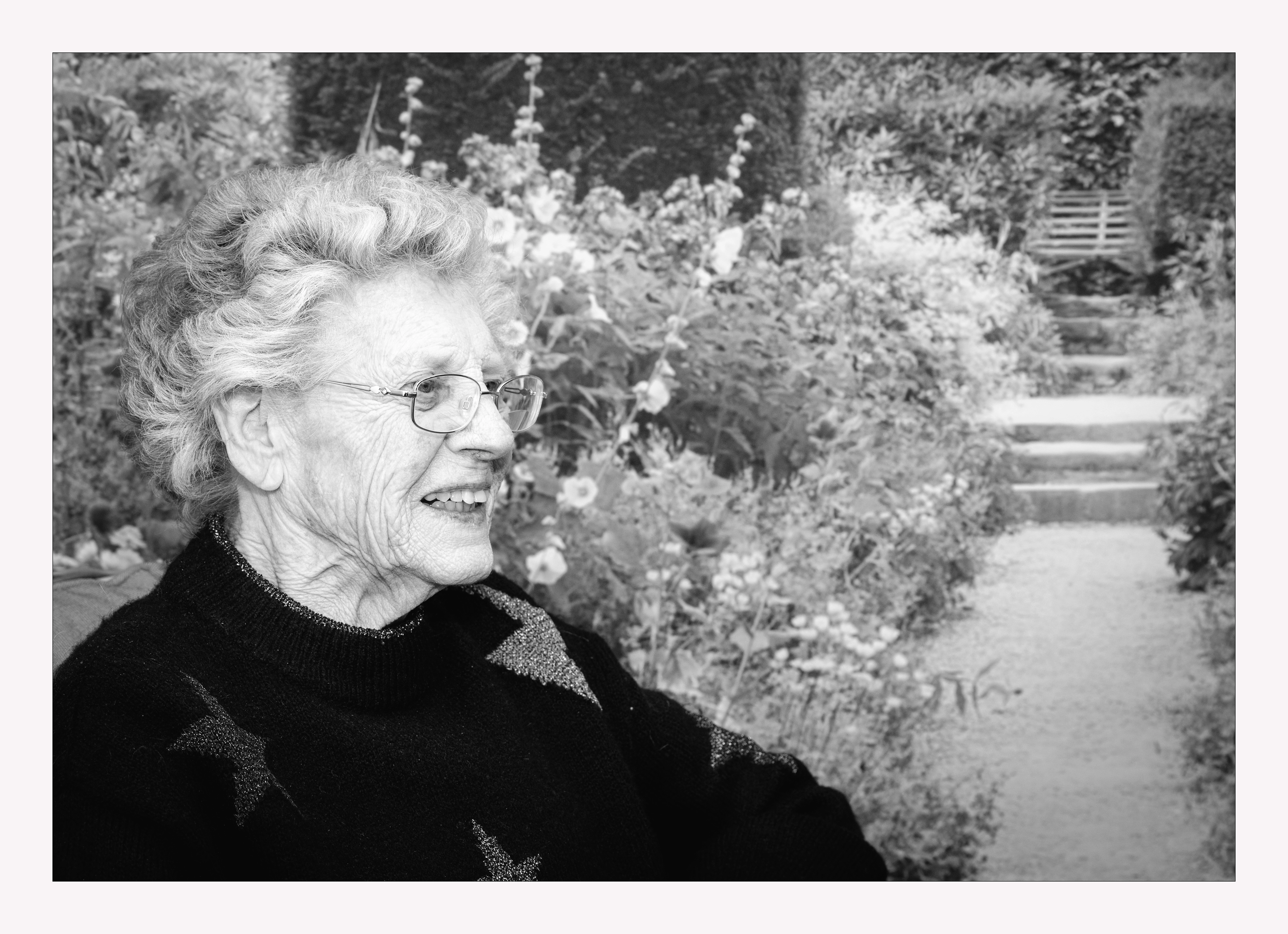 Black & White image of Lady sitting beside a garden picture